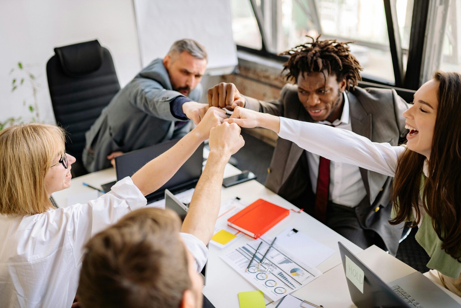 A team celebrating with a fist bump around a meeting table