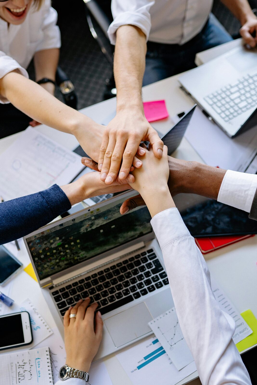 Team members joining hands over a desk