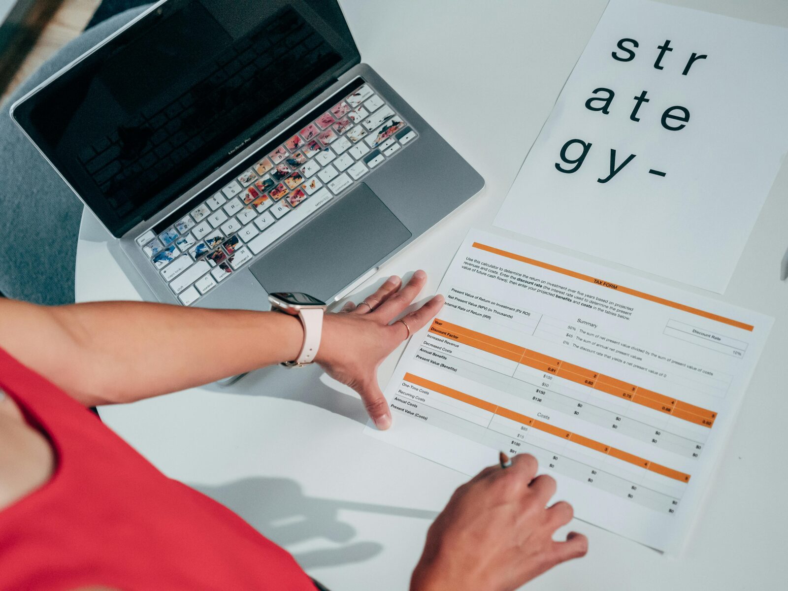 A hand on a printed property report next to a laptop and a 'strategy' note